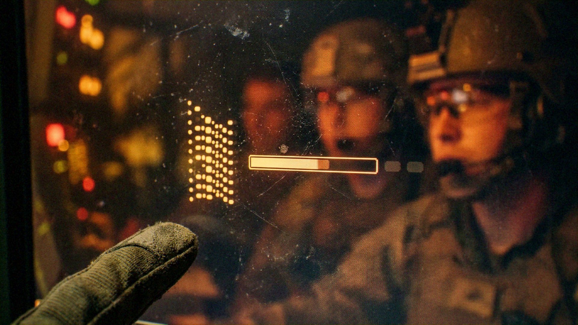 A gloved operator, a digital interface/display, and reflected military personnel in tactical gear. An active interaction where a human operator is monitoring or triggering a digital process within a team environment. Military technology and defense operations.